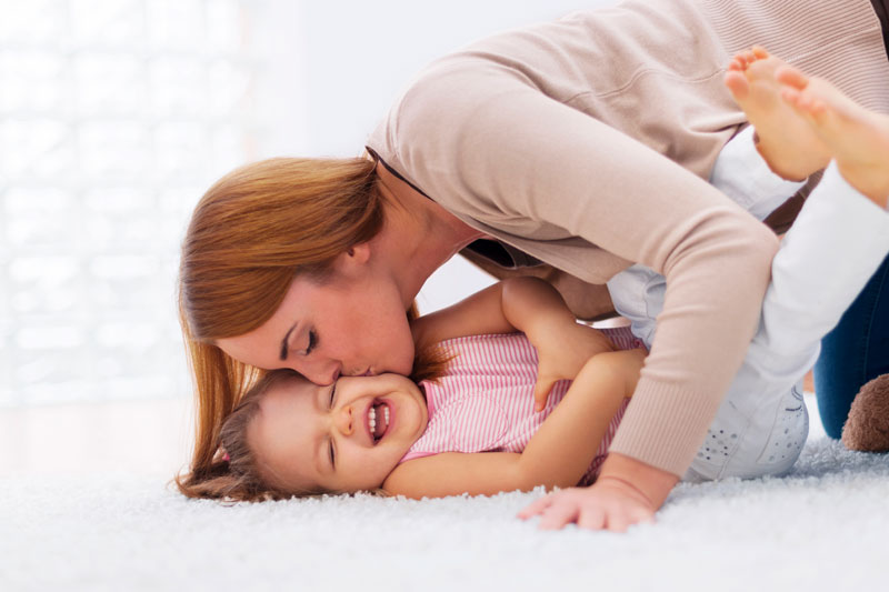 Mother playing and laughing with her toddler at home after successfully managing tantrum moments.