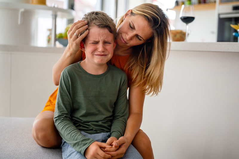 Mother comforting her crying child, showing empathy and support while talking about emotions.