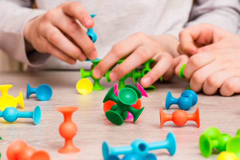 Close-up of a child practicing fine motor skills with colorful educational toys.